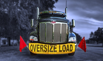 Oversize machinery secured on flatbed trailer with chains and straps